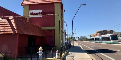 exterior of Mandhi House with a passing light rail train