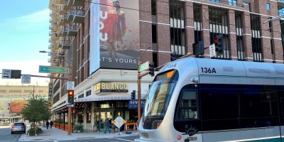 exterior of Blanco with a light rail train in the foreground