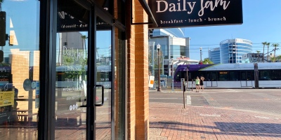exterior of Daily Jam with pedestrians and a light rail train in the background