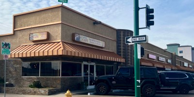 extrerior of the 5th Avenue Cafe with cars parked in front