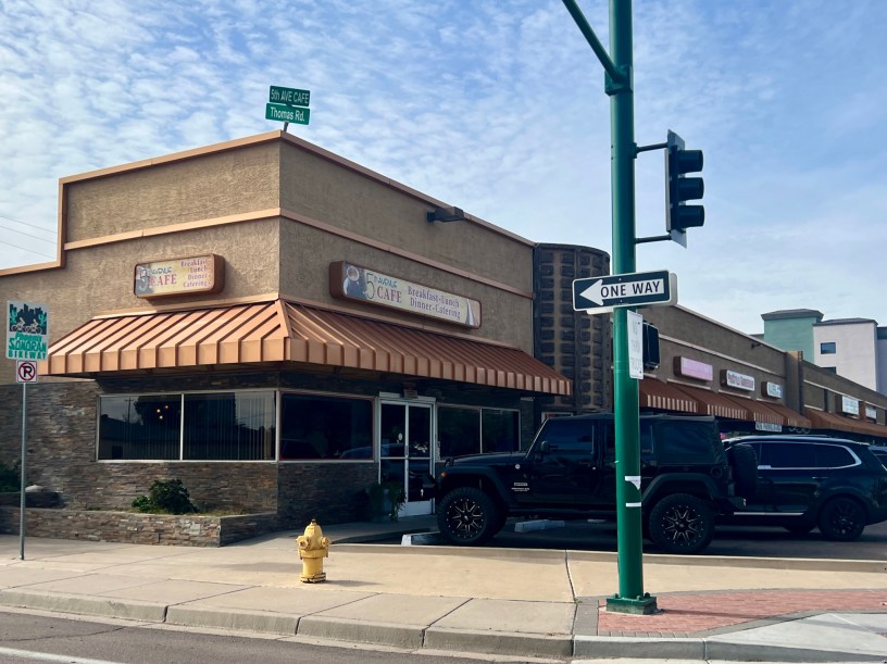 extrerior of the 5th Avenue Cafe with cars parked in front