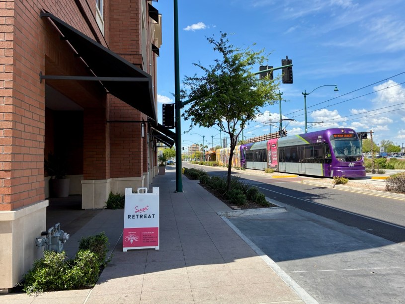 exterior of Sweet Retreat with a light rail train approach via Main Street