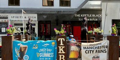 exterior of the Kettle Black as seen from First Street with a patio and sports and beer promotional materials