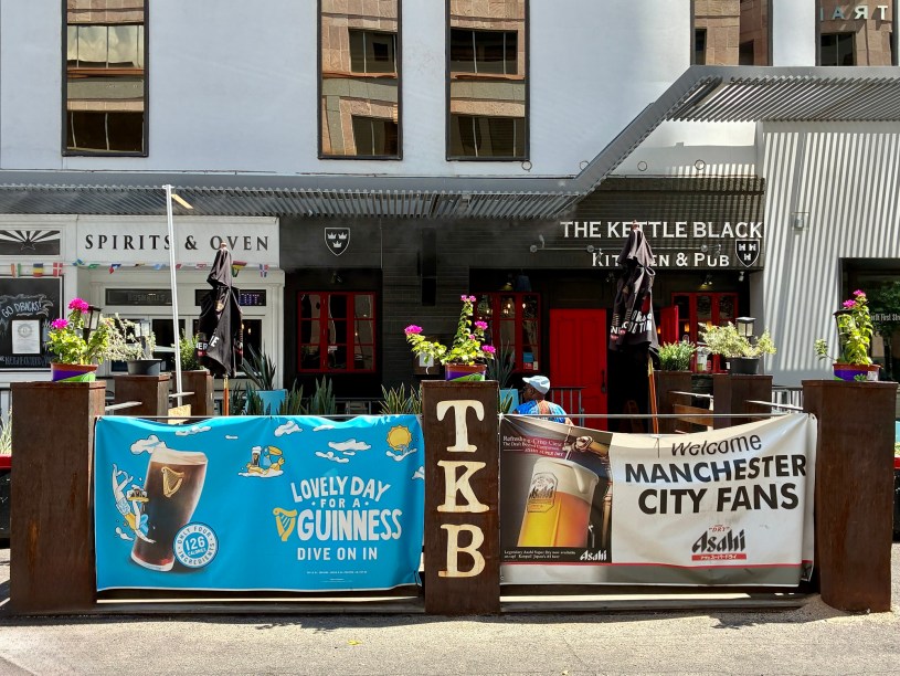 exterior of the Kettle Black as seen from First Street with a patio and sports and beer promotional materials