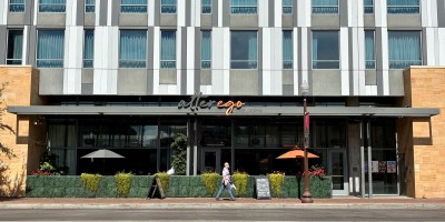 exterior of Alter Ego with the Canopy hotel above and a person walking on University Drive