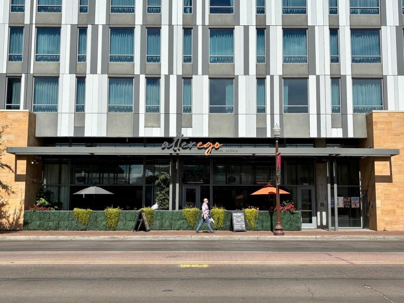 exterior of Alter Ego with the Canopy hotel above and a person walking on University Drive