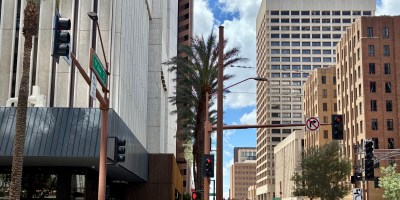 exterior of Centrico at the base of the 101 tower on the left with customers dining on the patio and a light rail train traveling along First Avenue on the right.