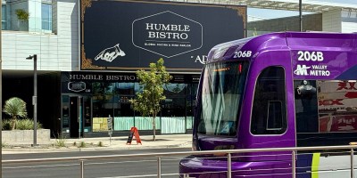 exterior of Humble Bistro with a light rail train passing in front of the restaurant